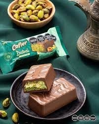 Cofler Dubai pistachio chocolate bar with pistachios on a green background.