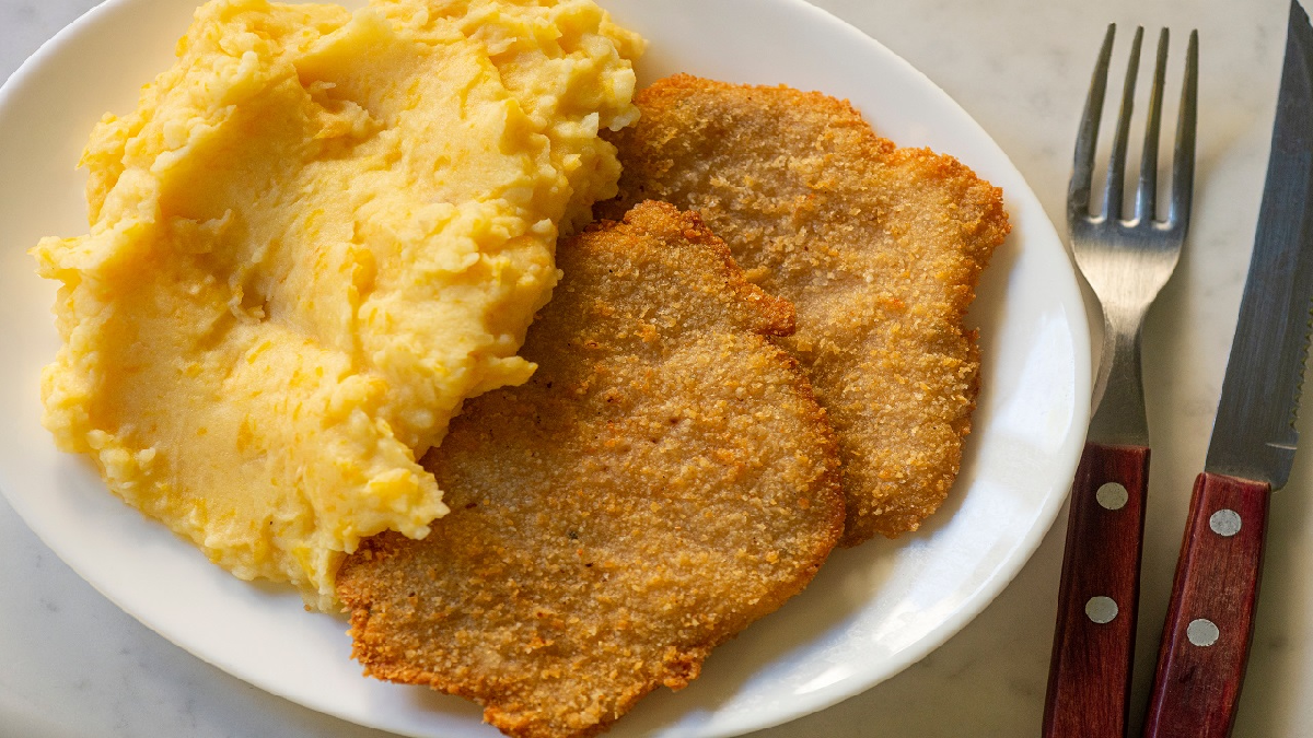 Argentine milanesa with mashed potatoes served on a white plate — a classic comfort food combination from Argentina. Argentine milanesa with mashed potatoes served on a white plate — a classic comfort food combination from Argentina.