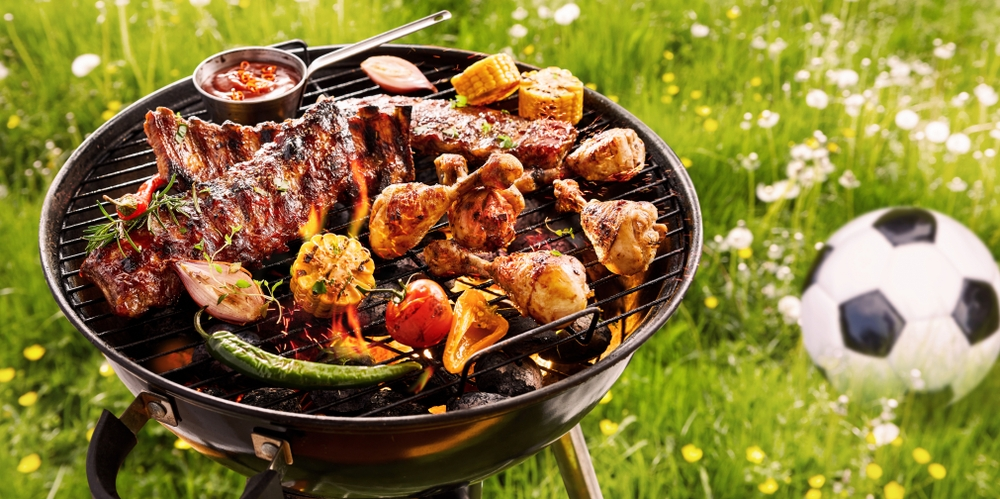 American-style BBQ with grilled ribs, chicken, vegetables, and corn on a charcoal grill outdoors on a sunny day. American-style BBQ with grilled ribs, chicken, vegetables, and corn on a charcoal grill outdoors on a sunny day.