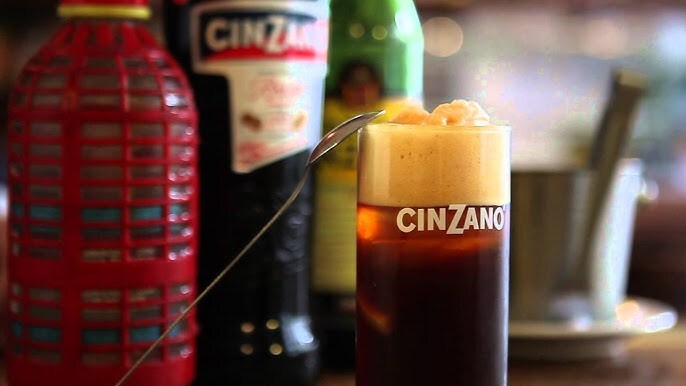 Vaso alto de Cinzano con Fernet con sifón y espuma, acompañado de botellas tradicionales argentinas al fondo