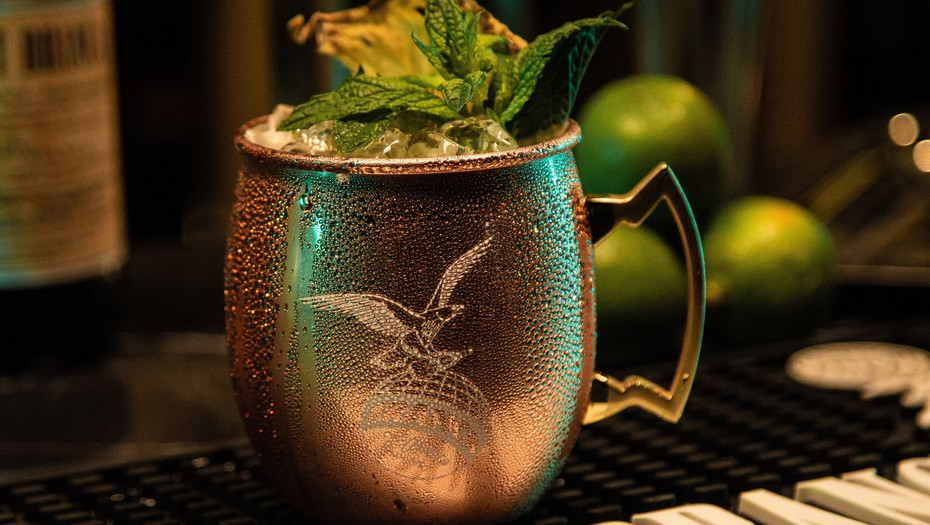 Trago de fernet de menta servido con hielo y hojas de menta fresca en vaso metálico