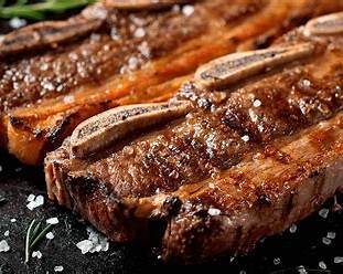 Grilled Argentinian beef ribs served with traditional chimichurri sauce on a wooden board Grilled Argentinian beef ribs served with traditional chimichurri sauce on a wooden board