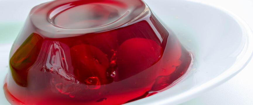 Red gelatin dessert served on a white plate, shiny texture with a light and fresh look. Red gelatin dessert served on a white plate, shiny texture with a light and fresh look.